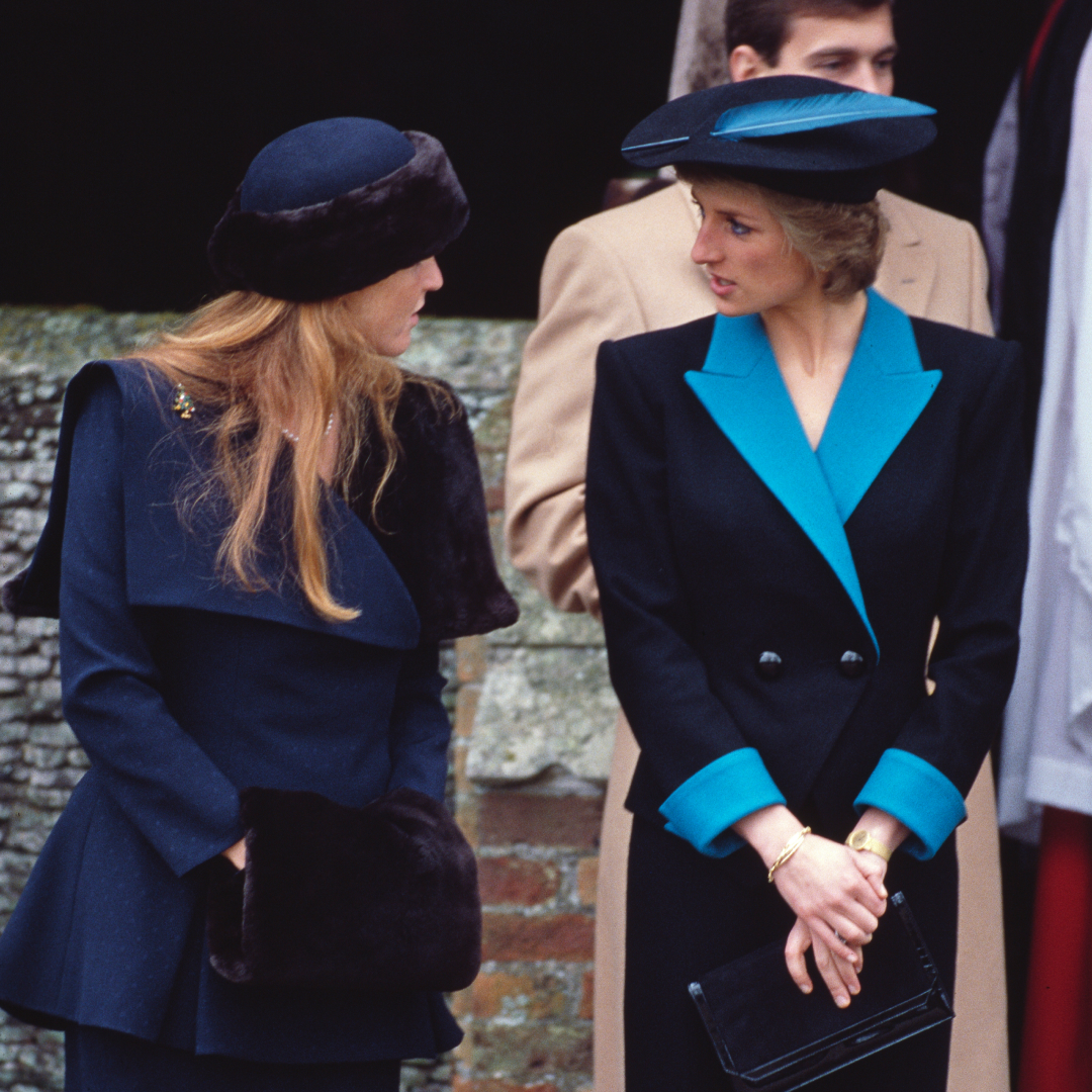 Sarah Ferguson and Princess Diana talking to each other wearing blue suits and hats