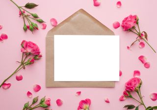 An envelope surrounded by pink flowers on a light pink background.