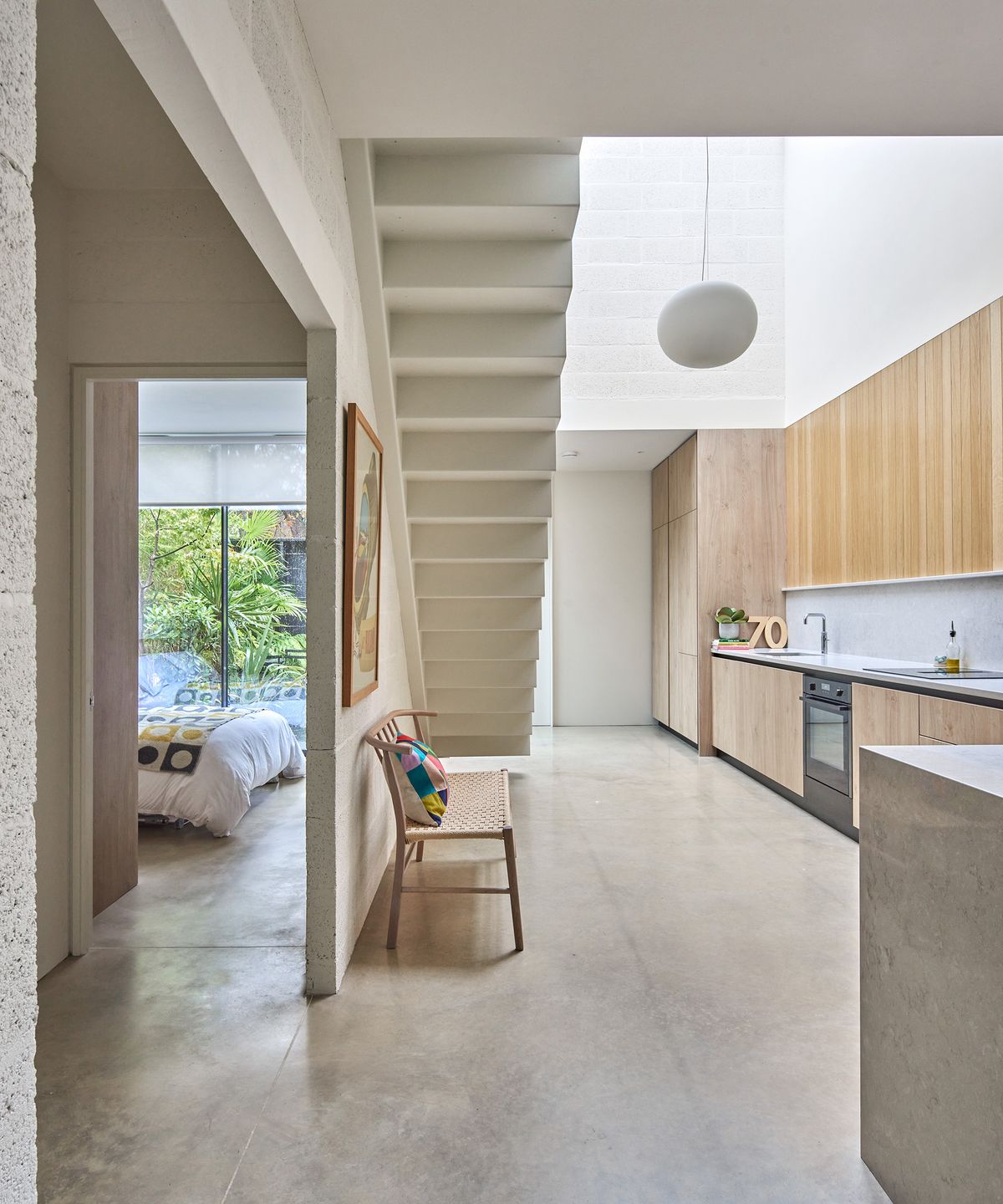 An open-plan kitchen and hallway with buff-coloured polished concrete flooring