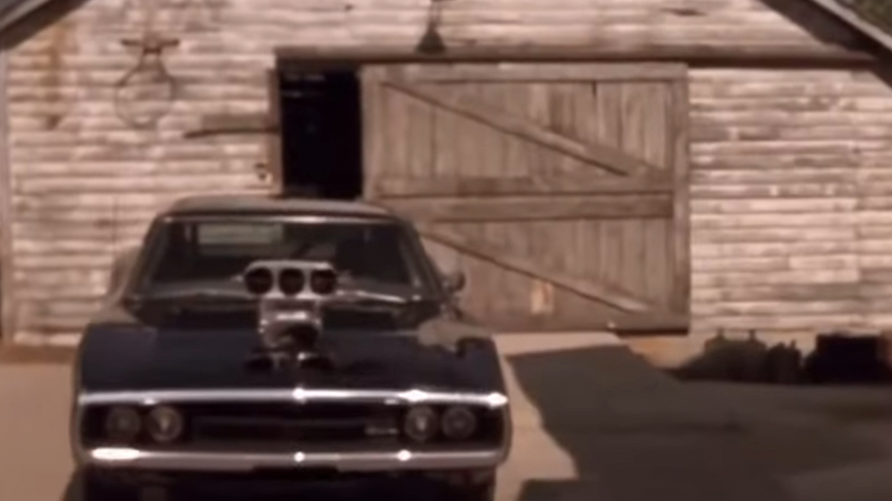 A black Dodge Charger from the front, in front of a garage