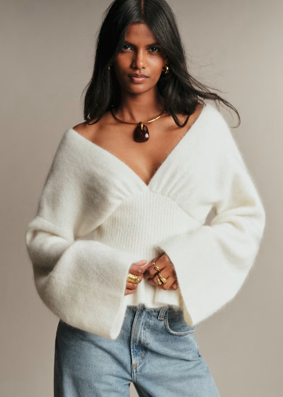 A model wearing a fuzzy white sweater with a deep V-neck