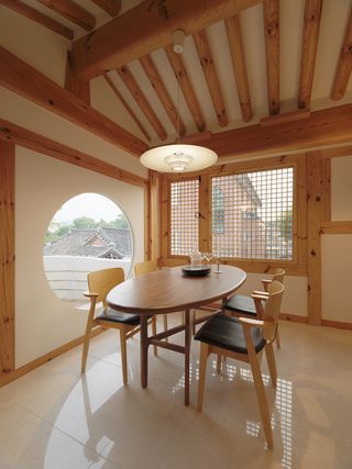 Seoul hanok dining room with wooden beams and window frames and wood and black table and chairs