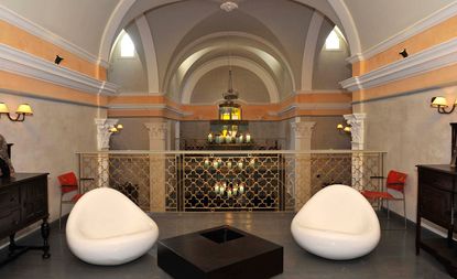 Interior of the L’Iglesia Hotel — El Jadida, Morocco with white low chairs, wooden furniture and intricate metal railings