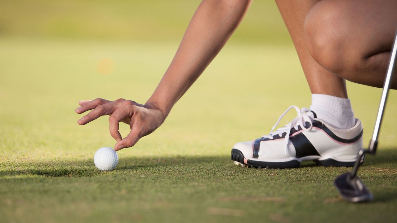 A golfer goes to flick a golf ball into the hole