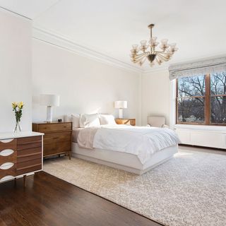 bedroom with wooden vanity white walls and chandelier