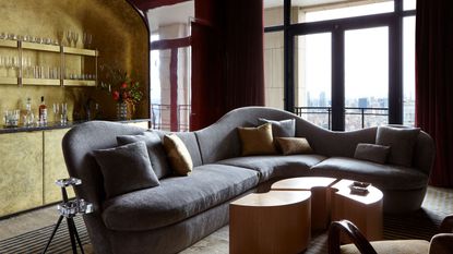 living room with deep red walls, gray sofa and a gold colored bar