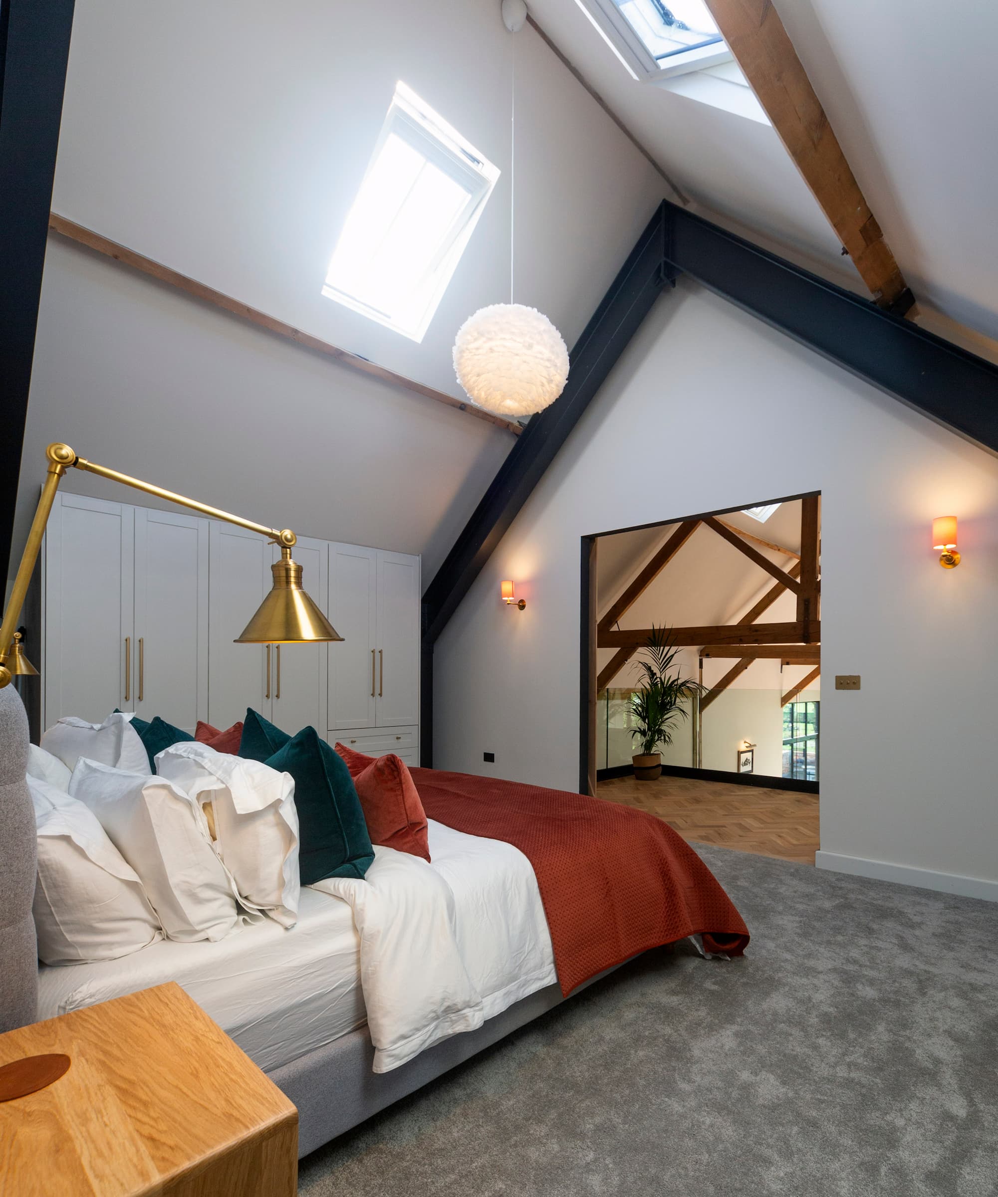 A bedroom with a triangle roof and dormer windows with grey carpet and orange wall lights