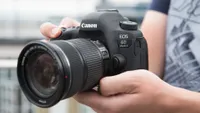 Hands holding the Canon EOS 6D Mark II full-frame DSLR