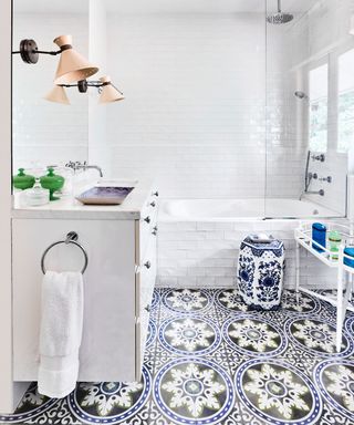 Bathroom with white wall tiles, white bath and handbasin and blue and white patterned floor tiles.