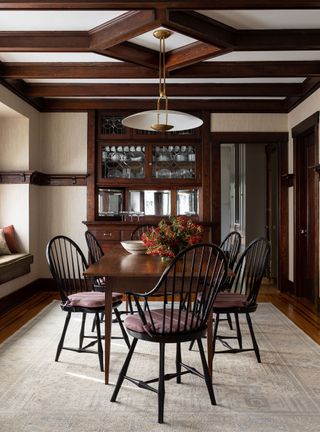 Small dining room with beamed ceiling and dark wood table and chair on pale beige rug