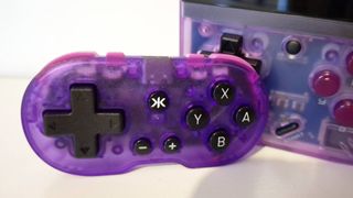 Photo of the Atomic Purple CRKD Atom controller sitting infront of a Miyoo Mini Plus handheld taken by writer Rosalie Newcombe.