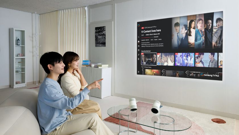 Samsung Freestyle Plus projector on table with screen on