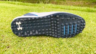 The outsole of the Under Armour HOVR Drive 2 SL golf shoe as shown on a golf course