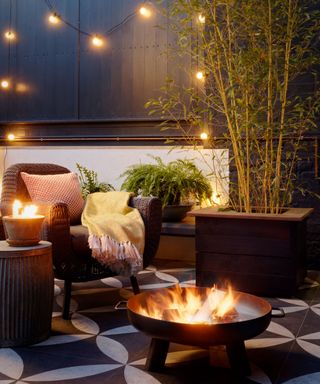 fire pit on a patio with string lights along a fence