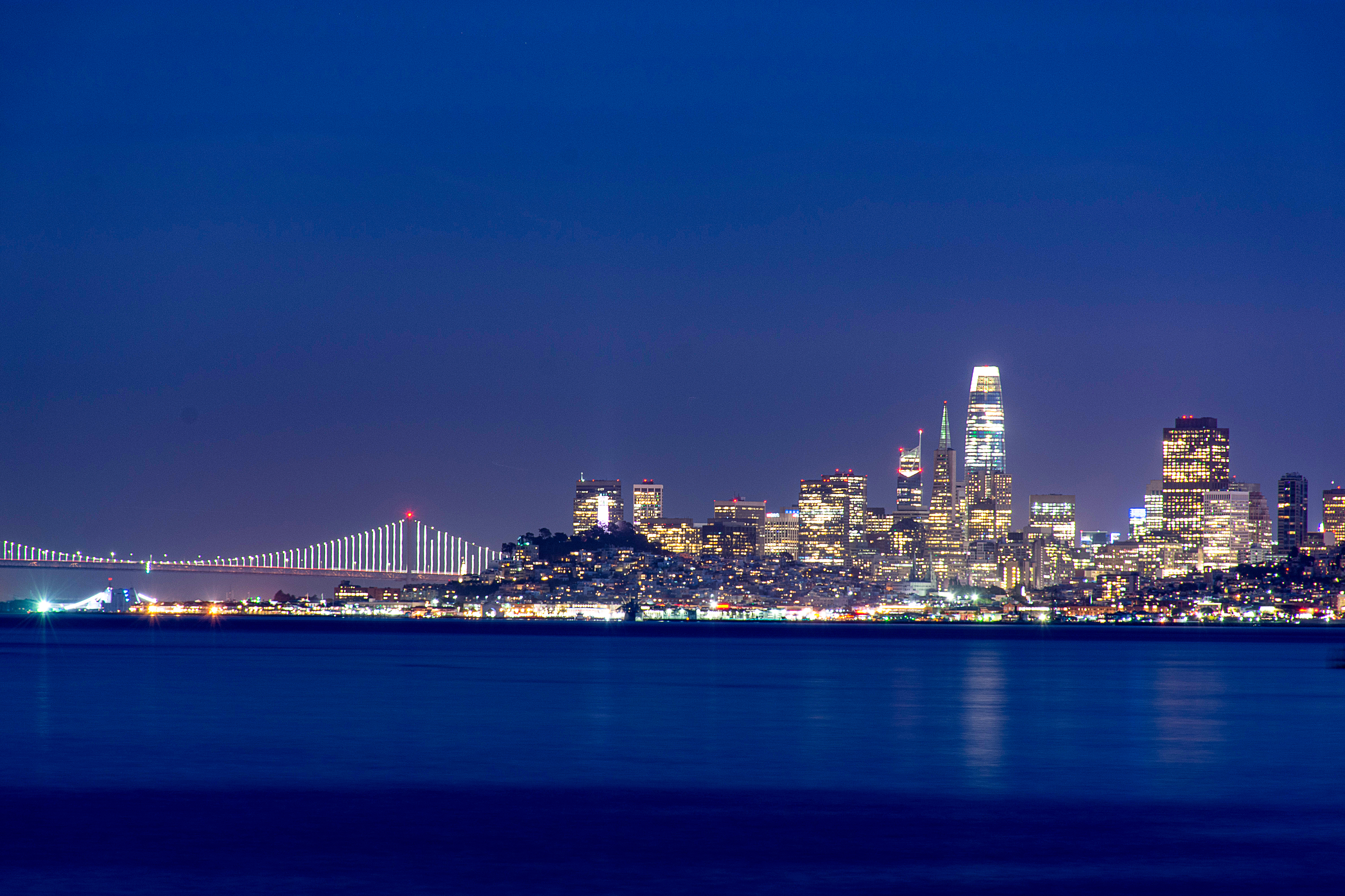 The San Francisco skyline and Bay Bridge lit up at dawn as seen from across the bay in Sausalito