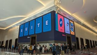 The conference floor at SuiteWorld 2023, at Caesars Forum in Las Vegas. On a large screen that wraps around a wall, the word 'SUITE' is written on graphical representations of playing cards.