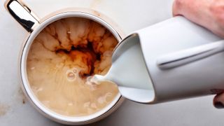 Cup of tea with milk being poured in