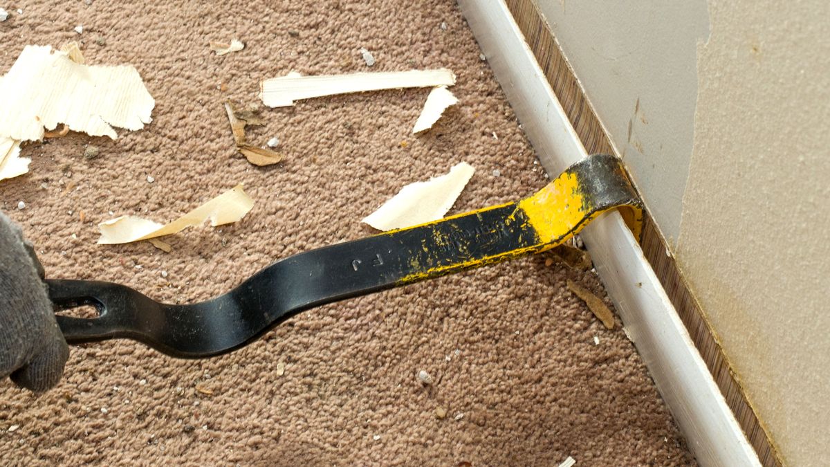 Crowbar easing skirting board away from wall 