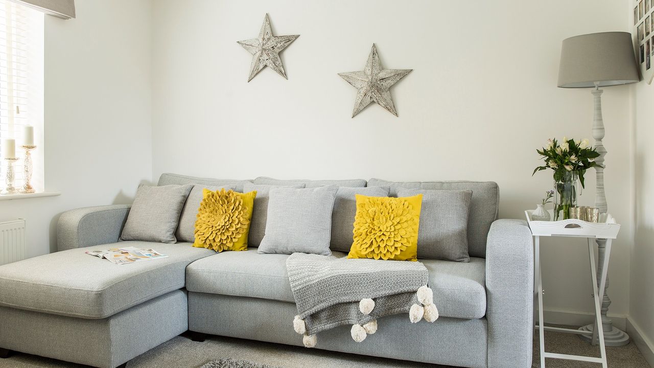 living room with white walls grey sofa and lamp