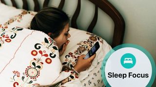 A young girl in bed with tapestry pattern sheets, laying on her front using a mobile phone as she yawns. With inset of Apple Sleep Focus logo