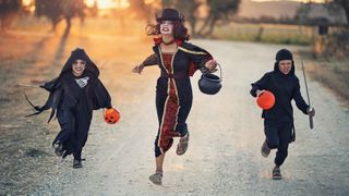 Woman and two children running in Halloween costumes