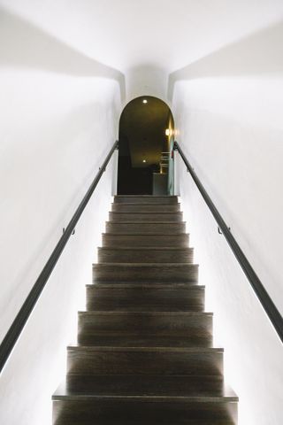 Long staircase, looking up to an arched door at Manifest Washington designed by Snarkitecture