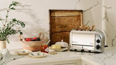 A marble kitchen counter with a silver toaster, a wooden chopping board, and bowls on top of it