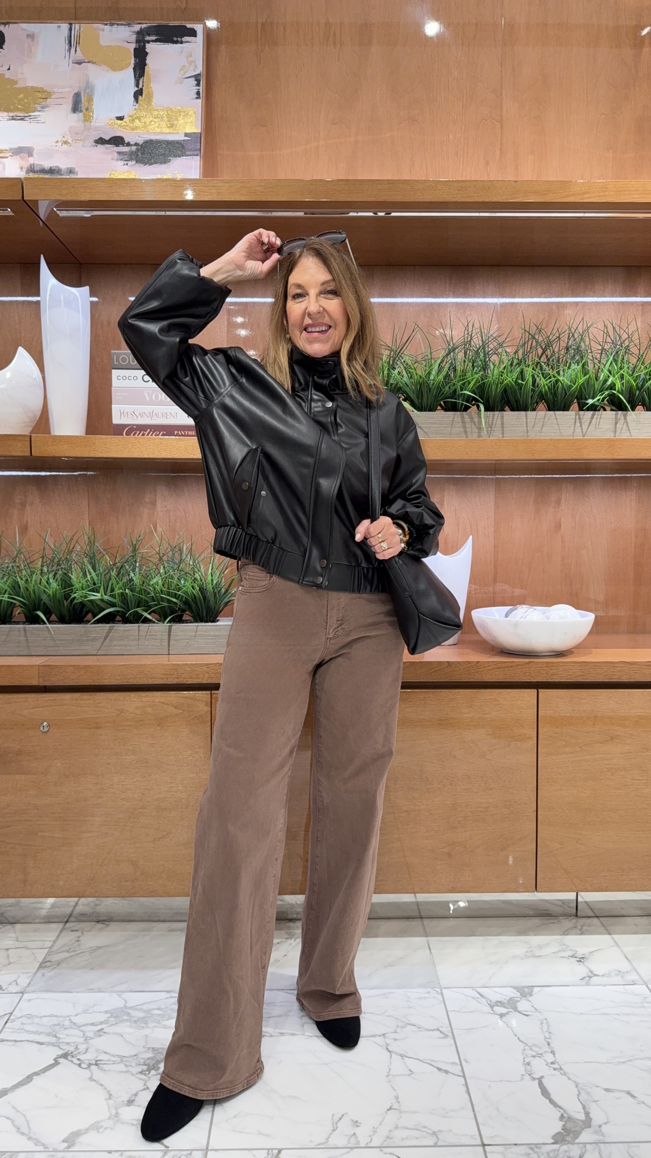 Sandy Koszarek wearing a funnel-neck leather jacket and brown jeans.