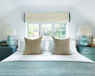bedroom with teal bedside chests, aqua lamps, teal throw, yellow patterned cushions and yellow patterned blind