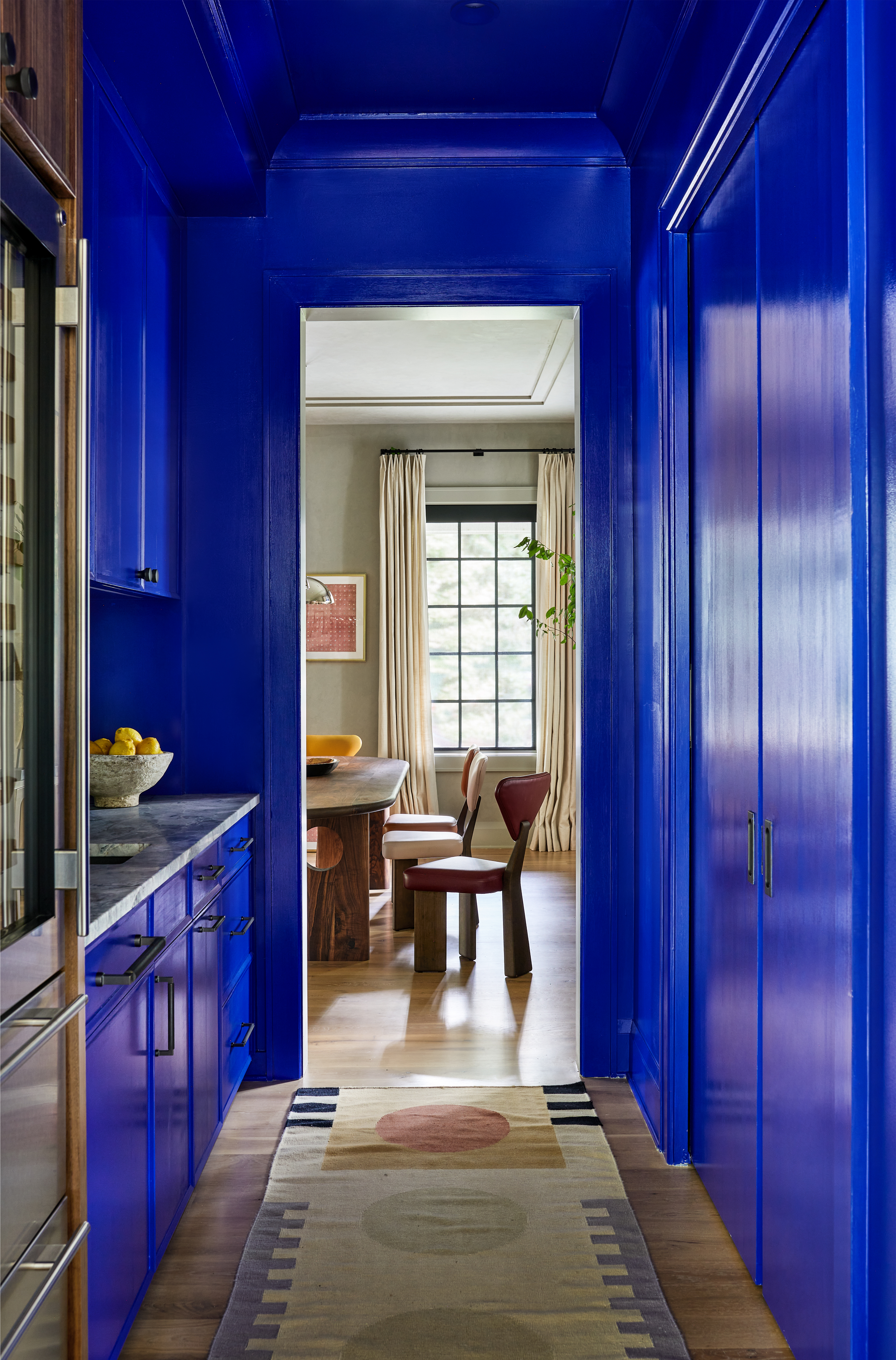 A galley kitchen drenched in electric blue, with a carpet in the centre