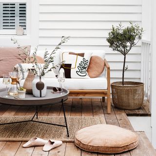 Rustic wooden decking area with lots of rugs, cushions, and furniture