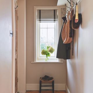 narrow entrance hall with linen blind at window and high shelf with vintage iron coat hooks