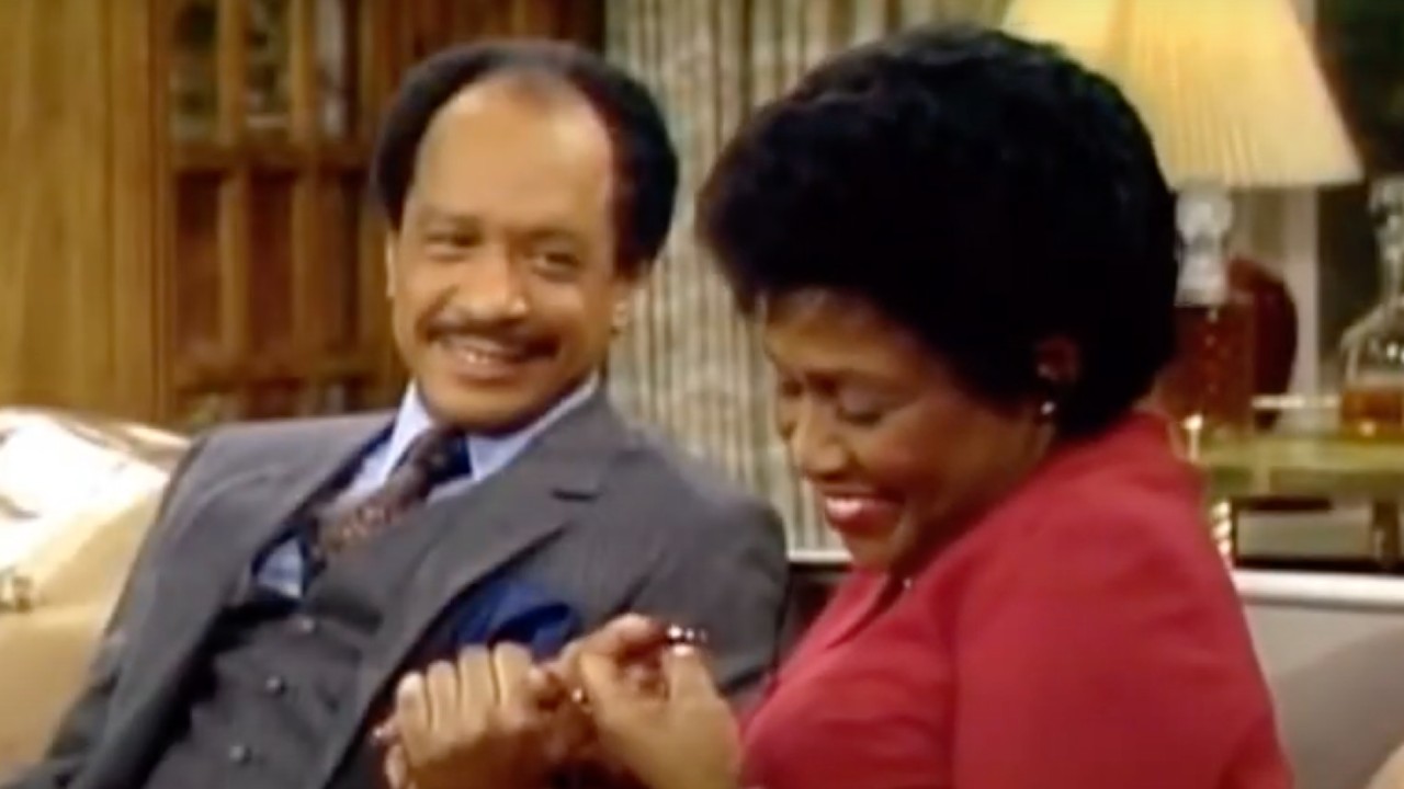 Louise and George Jefferson sitting on the couch in The Jeffersons.
