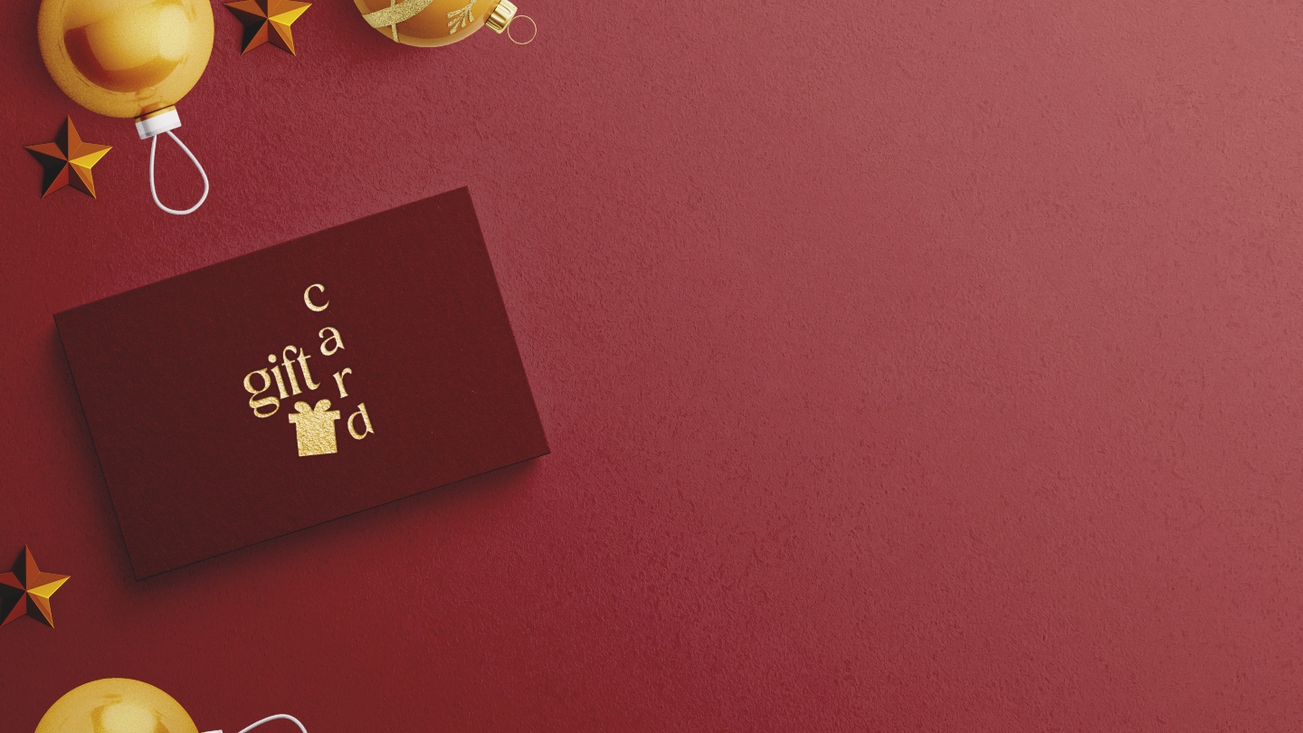 A red background with Christmas decorations with a red gift card in the middle on the left