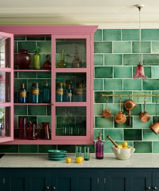 Pink cabinets in front of green tiles