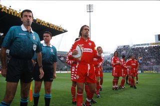 Fiorentina captain Gabriel Batistuta standing next to the referee, holding a pennant.