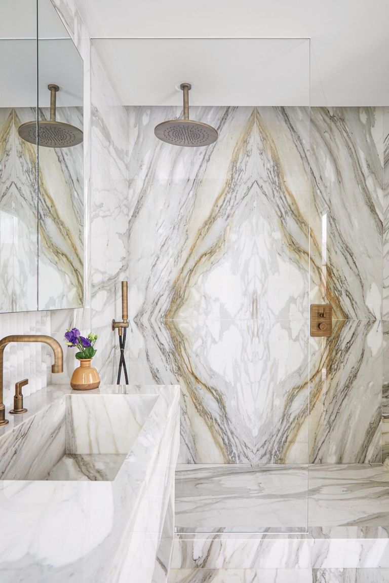 Walk-in shower ideas with luxe deep marble veining on the wall and floors and gold taps shower room