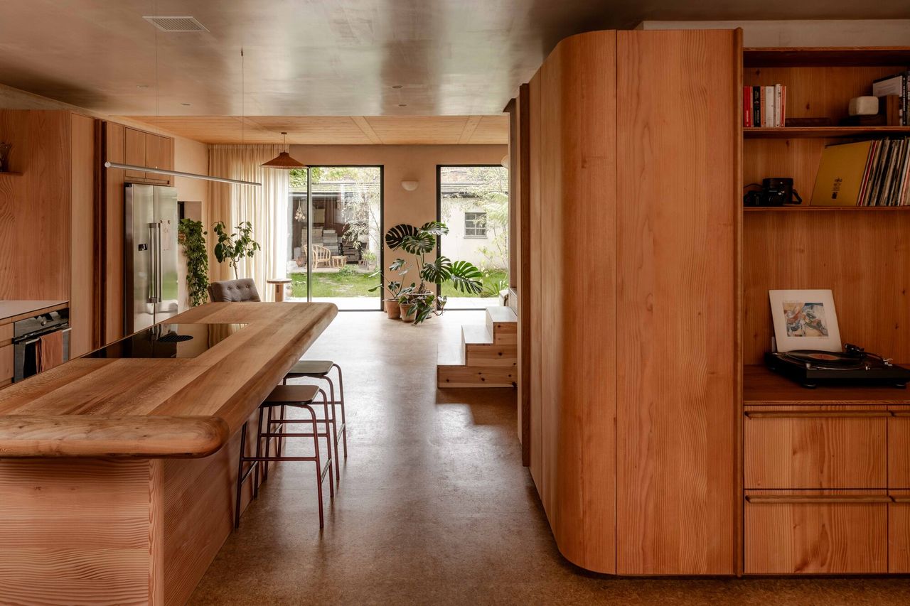 open plan home with curved timber cabinetry, curved kitchen countertop, cork flooring, and gloss ceilings