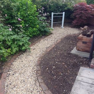 Gravel path with brick border next to bare soil patch