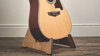 An acoustic guitar on a guitar stand in a living room