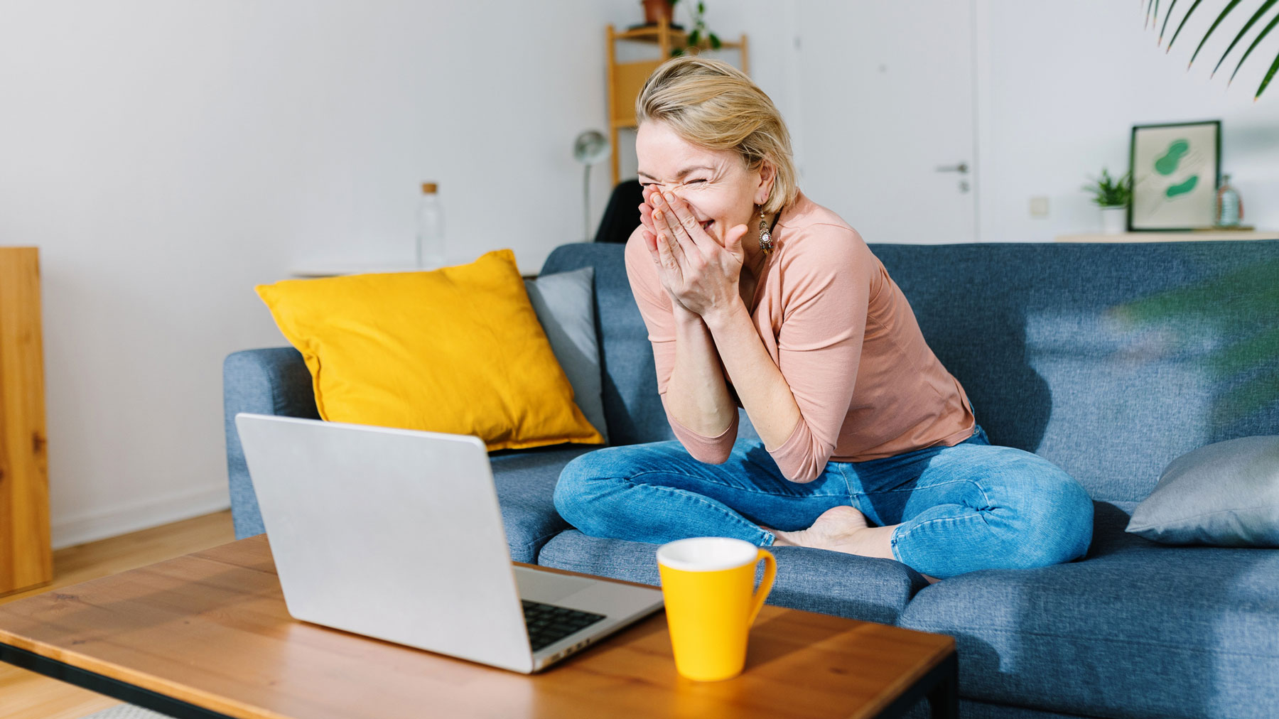 Women sitting at screen laughing with hands on face