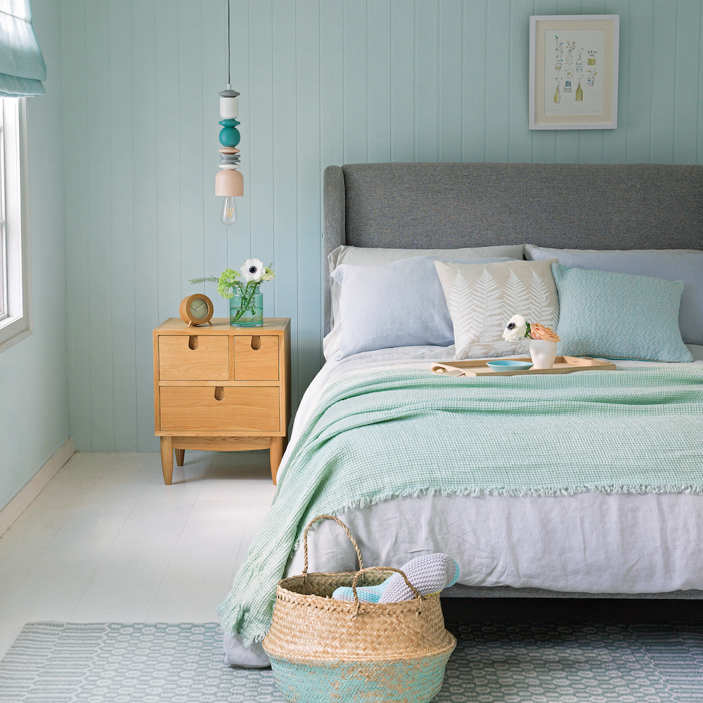 bedroom with wooden flooring and double bed with cushions