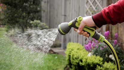 A hand uses a garden hose