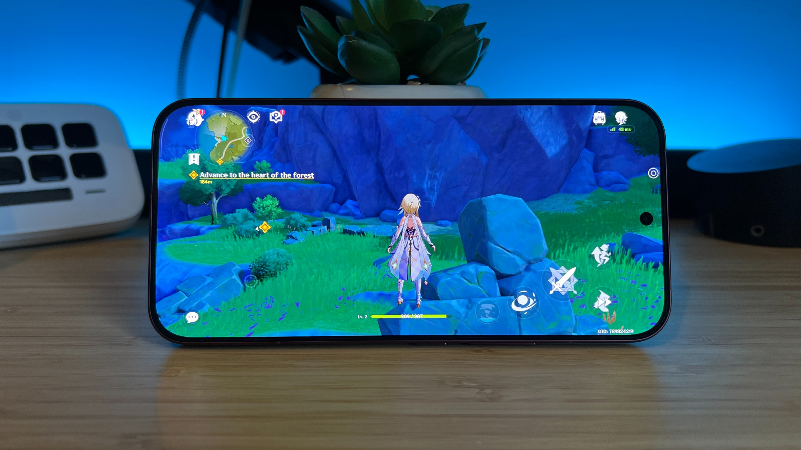 Genshin Impact running on a Poco F9 Ultra smartphone stood up on a wooden table