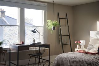 bedroom with home office, window film at window, storage ladder, neutral scheme