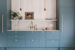 kitchen with deep blue shade kitchen cabinetry and and exposed lightbulbs, an example of the successful kitchen planning by husk