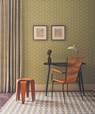 desk and chair with greenpatterned wallpaper behind and patterned rug