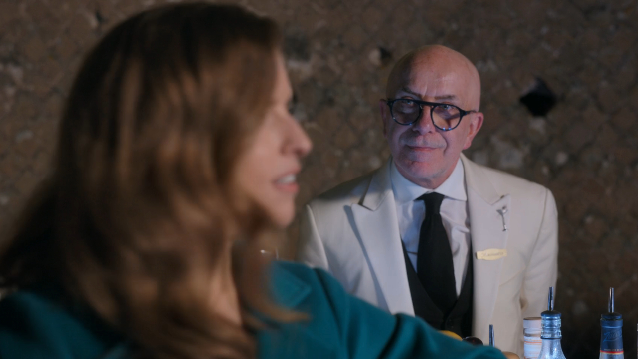 Alessandro Palazzi looks expectantly at Anna Kendrick as she stands at his bar in Another Simple Favor.