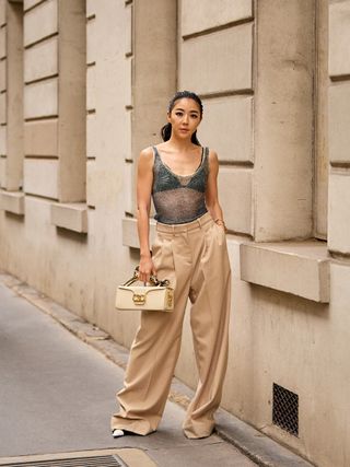 a photo of a woman wearing a cute bralette under a sheer crystal mesh top with trousers