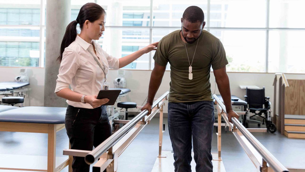 Guy walking between balancing poles, doctor steadies him